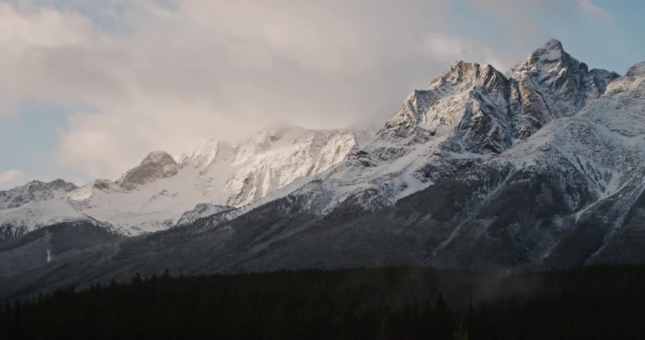 The mountain range is covered with fresh snow and clouds