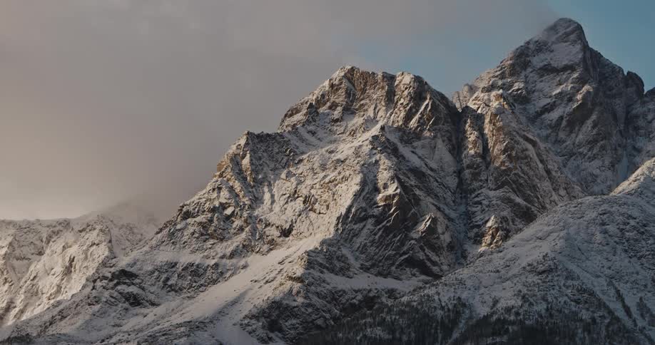 Fresh snow and fog covers rocky mountain range at dawn
