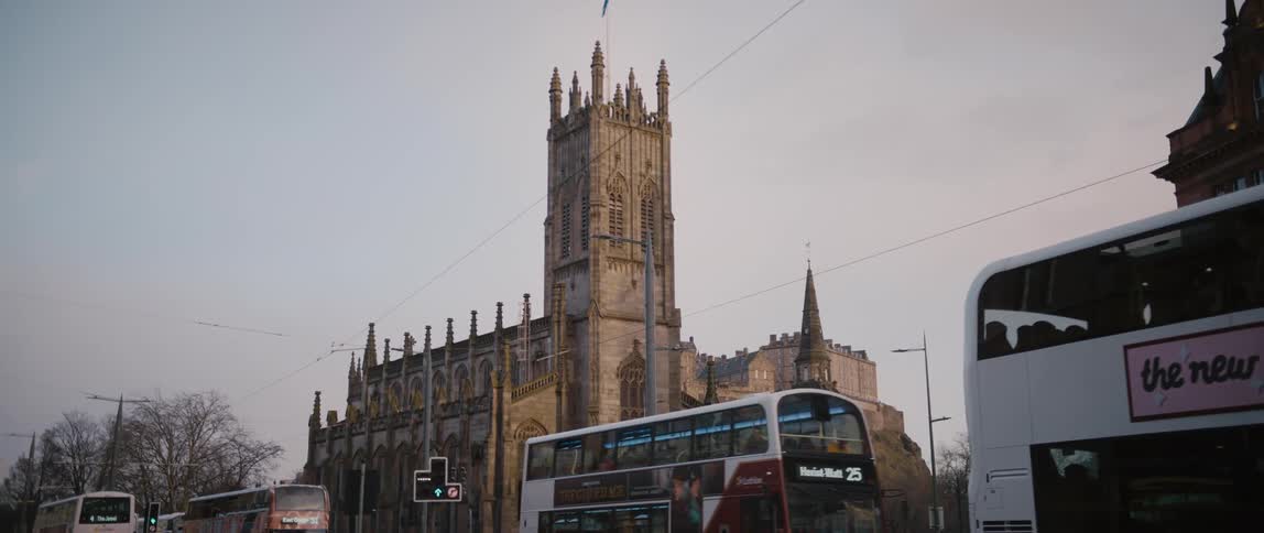 A long line of tourist passenger buses pass by St. John's Scottish Episcopal Church in Edinburgh, Scotland.