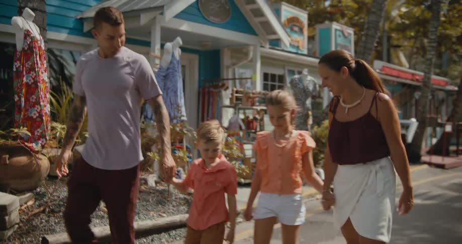 A family holds hands while watching past the front of shops