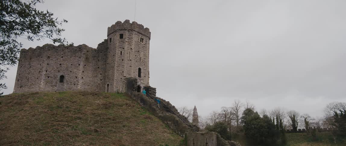 A small castle on a hill under a cloudy daytime sky