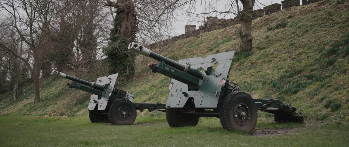 Military cannons near a grassy hill