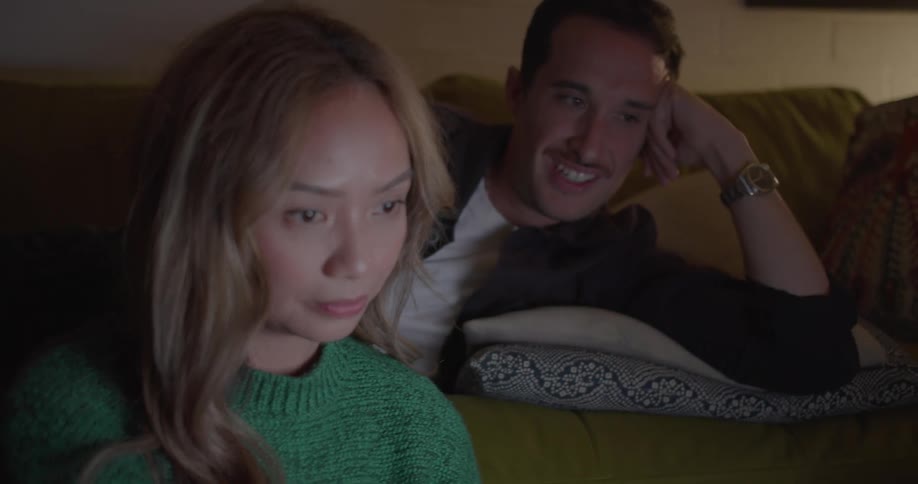 A couple laugh and chat while sitting in their living room
