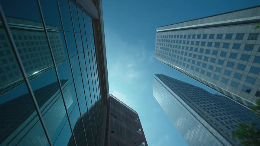 Tall buildings with lots of windows sit next to the palm trees under a sunny blue sky