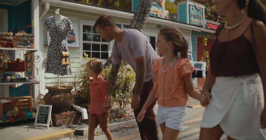 Mom and dad walk down a tropical village street each holding a childs hand