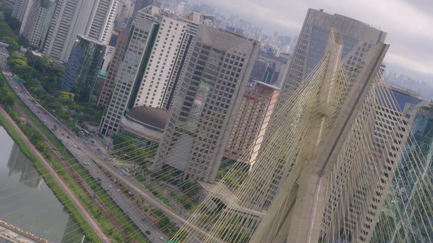 Cars travel on a highway that runs between a river and skyscrapers in a city