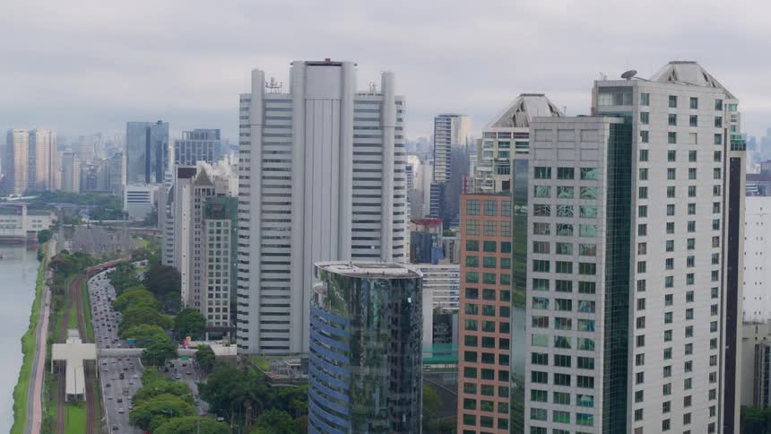 Boats on the river next to the highway in the city and the skyscrapers under a cloudy sky