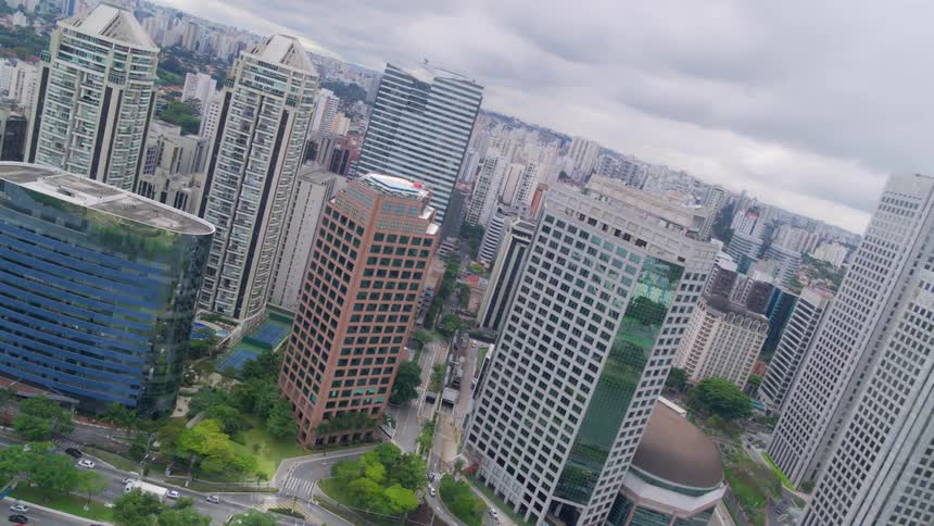 Cars travel on the city streets near the tall buildings and the river