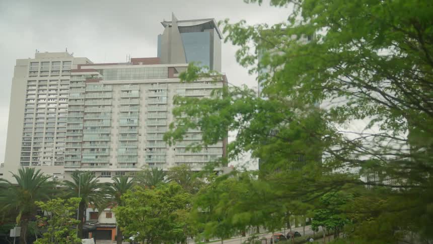 An aerial view of an apartment building and an office building in a city as cars drive down the street and a person bikes
