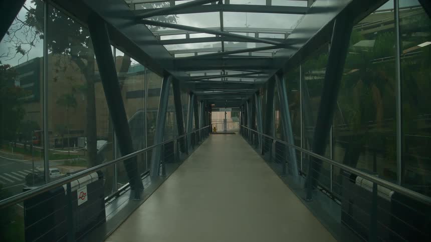 Enclosed pedestrian walkway crosses street toward building near intersection