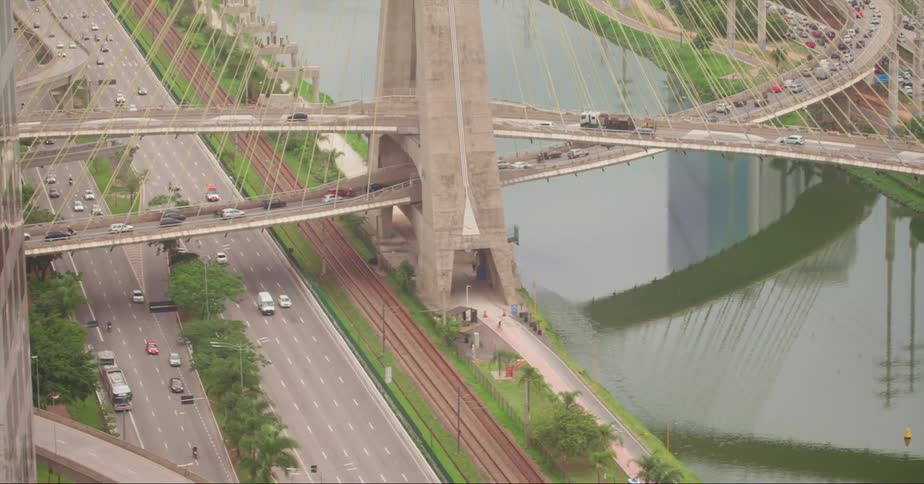 Traffic moves across a bridge over a river and train tracks