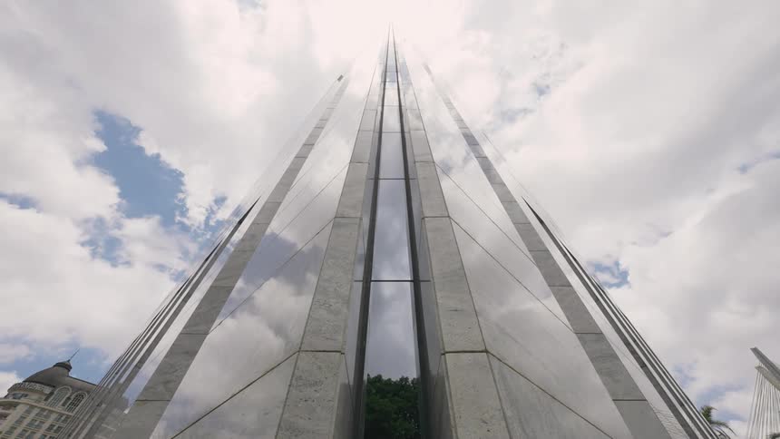 Timelapse of white clouds over a massive skyscraper that has lots of windows