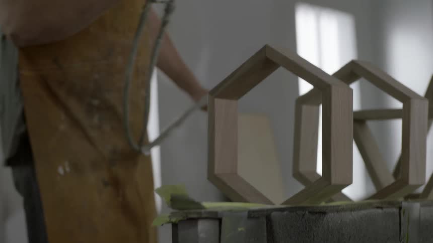 A person sprays wooden shapes