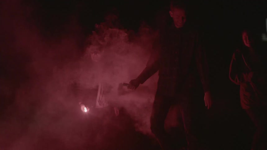 People are walking outside at night some have flares