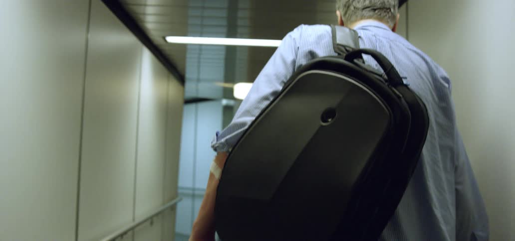 A man carrying a backpack walks down a corridor in an airport