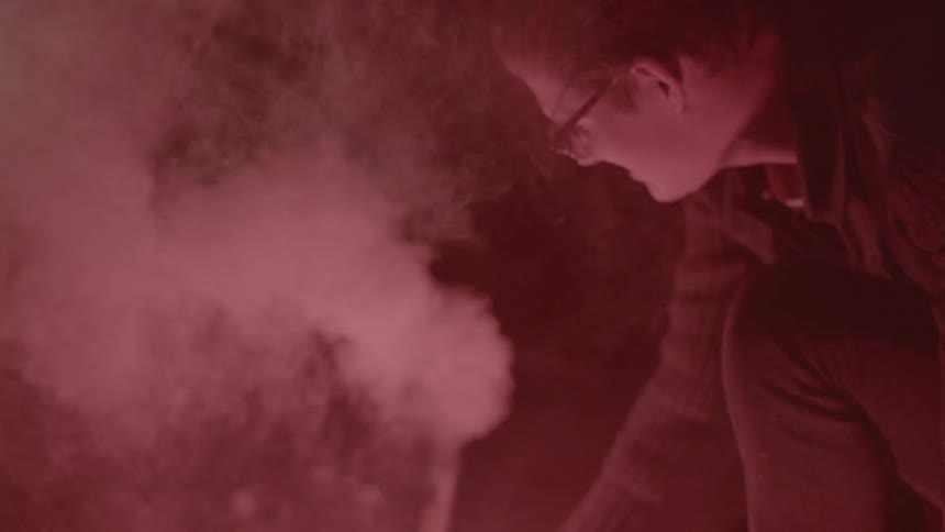 Smoke rising around a man as he lights fireworks