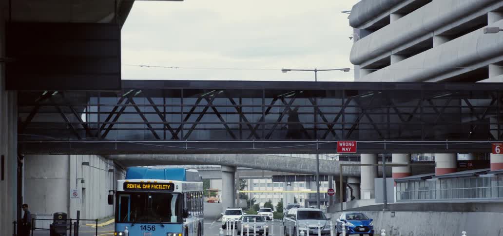 People walking across a pedestrian bridge with bus and car traffic underneath