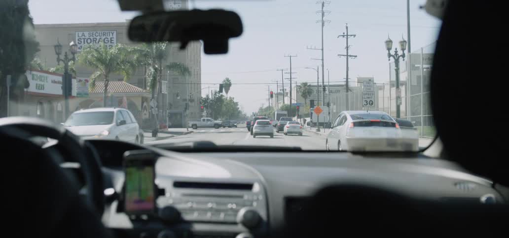 Rear view mirror reflects person driving along street toward intersection