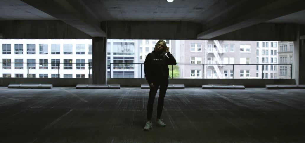 Woman wearing a hoodie standing in the middle of an empty room alone