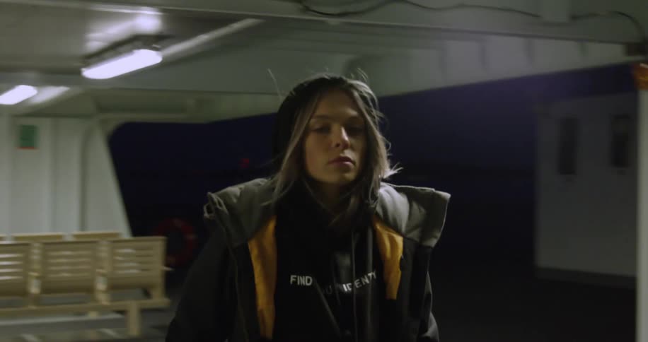 A woman in a jacket walking down a hallway at night