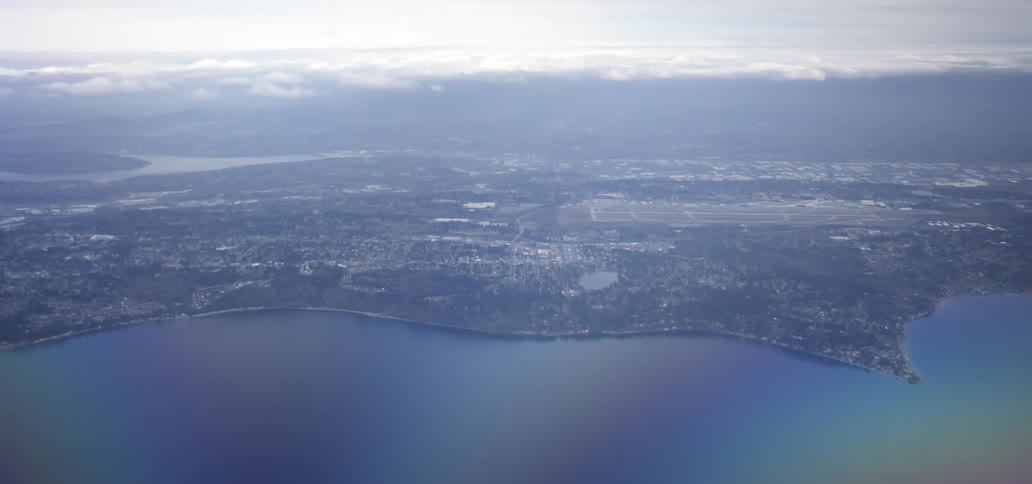 An aerial view of a coastal area shows a sprawling landscape