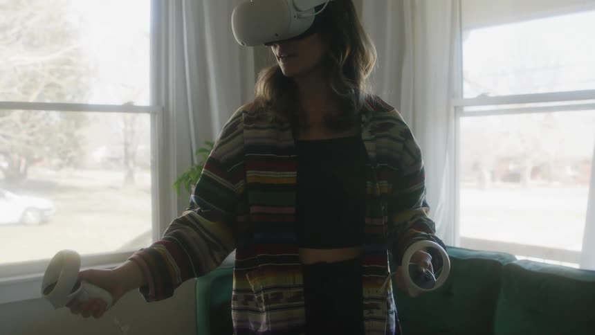 A woman uses a virtual reality headset in the living room of a house during the day