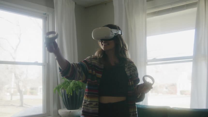 Woman with brown hair equipped with a vr headset uses virtual reality in living room at home