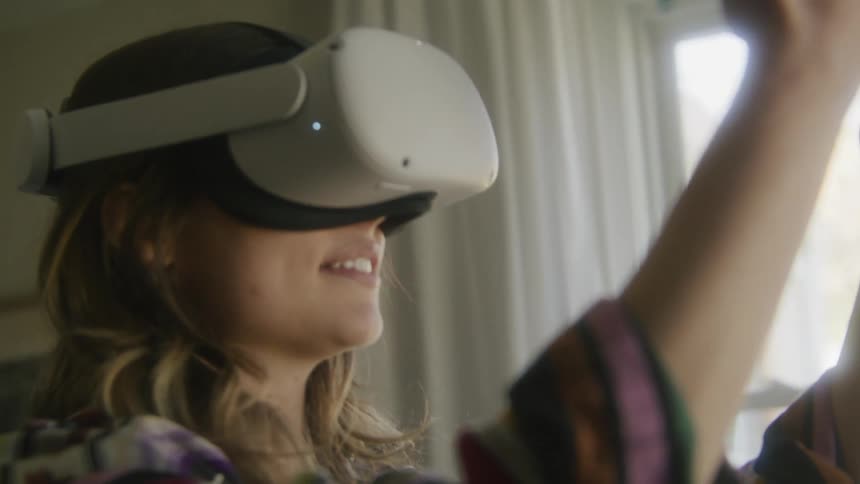 A woman smiling while wearing a virtual reality headset at home