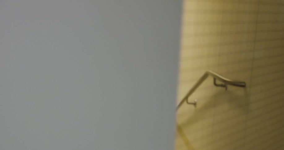 A woman in a hoodie walks to a stairwell and opens the door to it before walking downstairs