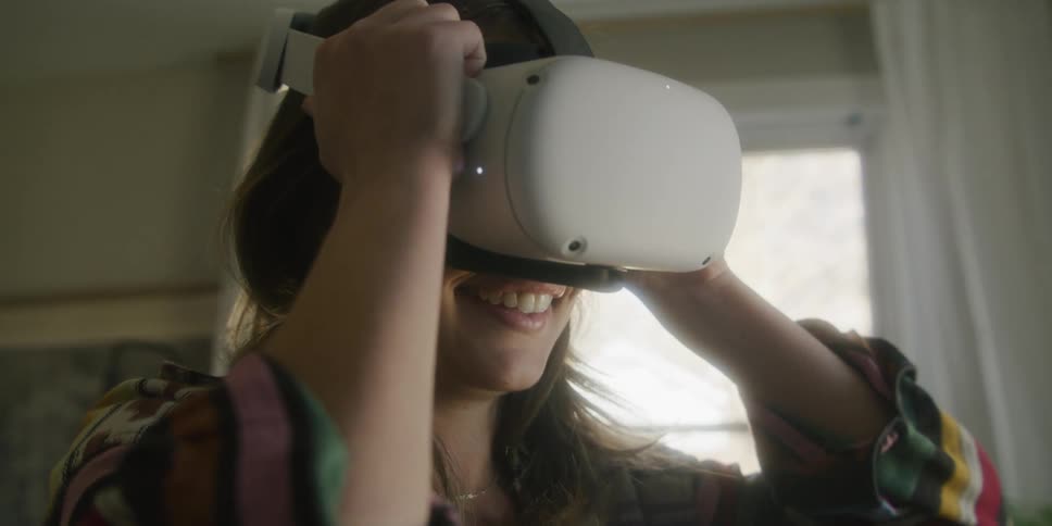 A girl has a smile on her face as she puts on a virtual reality headset