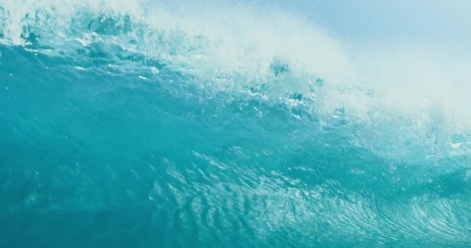 A large wave crashes in the ocean on a sunny day