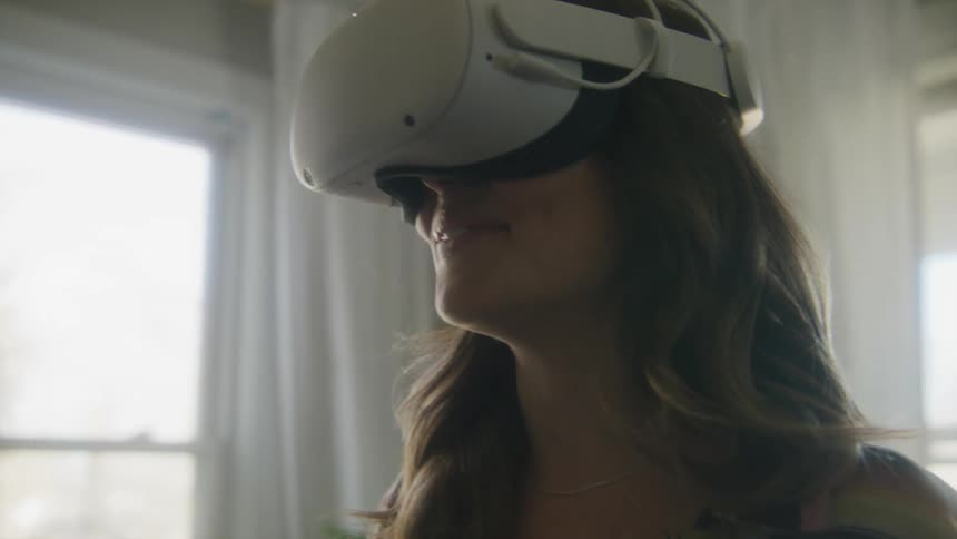 A woman smiling and laughing while using a virtual reality headset at home