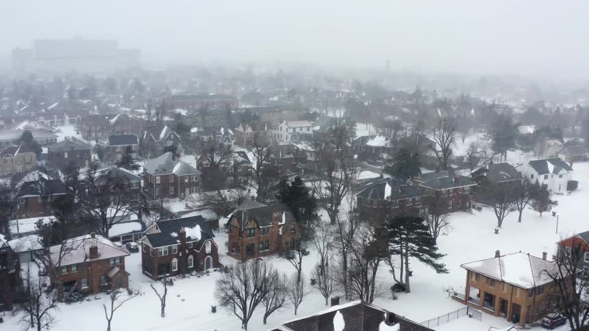 A residential neighborhood engulfed in a snowstorm on a foggy day