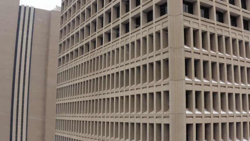 An aerial view of a large concrete building in a city during a snowstorm
