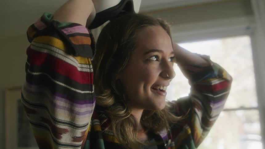 A girl has a smile on her face as she takes off a virtual reality headset