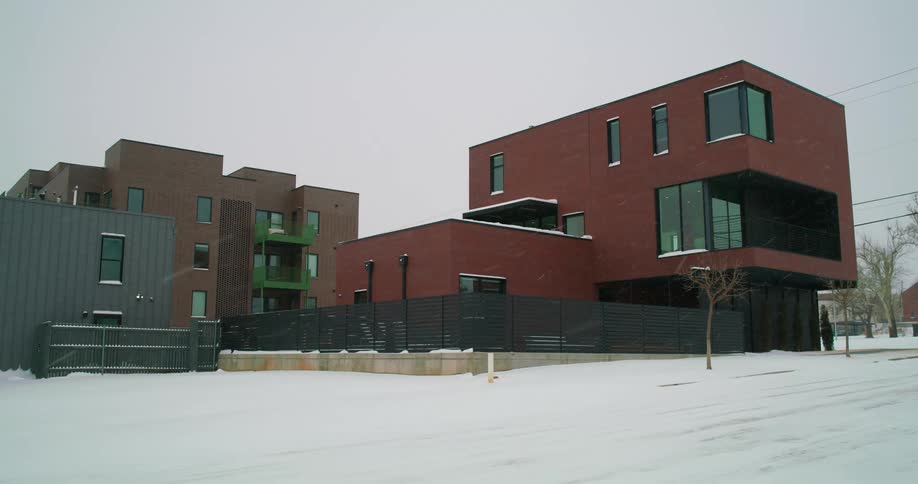 Snow falls and covers the street in a neighborhood with modern style homes