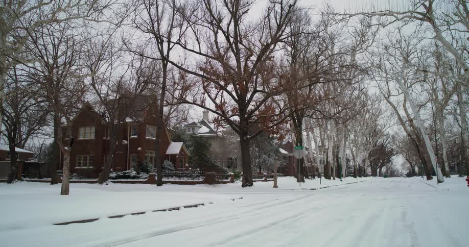 Light snow falls on a neighborhood street on a winter day