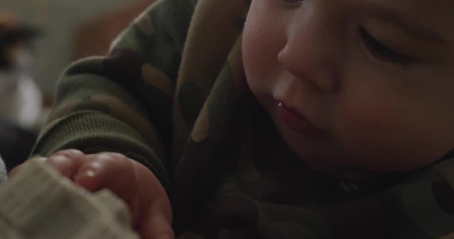 A boy reaches for a toy and picks it up