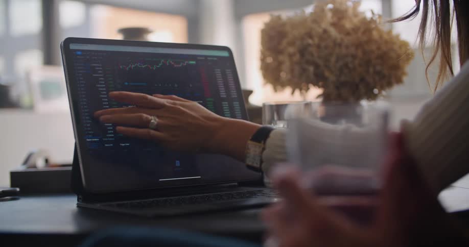 A woman in an office points to a laptop as she talks to a man