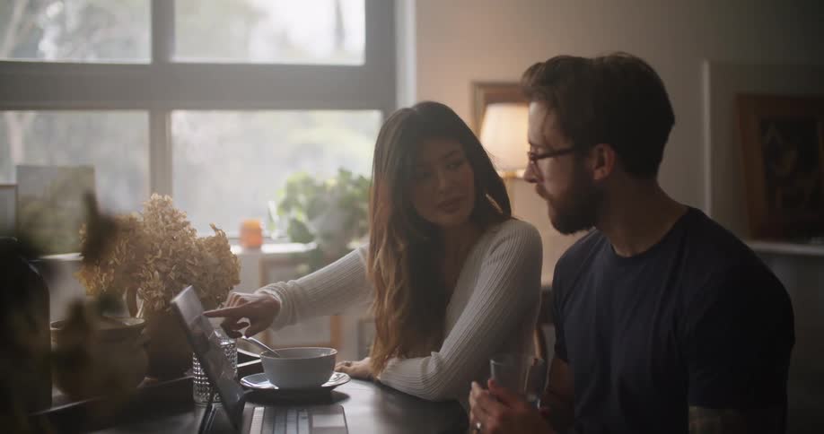 Coworkers sit at table in office discussing contents of laptop screen