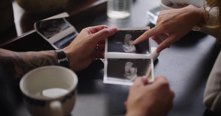 Man holding a picture and showing it to a woman while they both talk about it