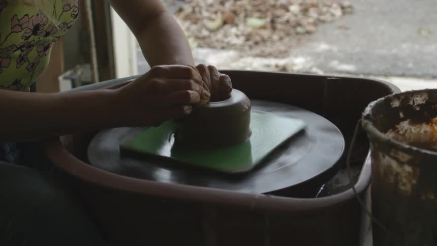 A woman shaping clay on a pottery wheel