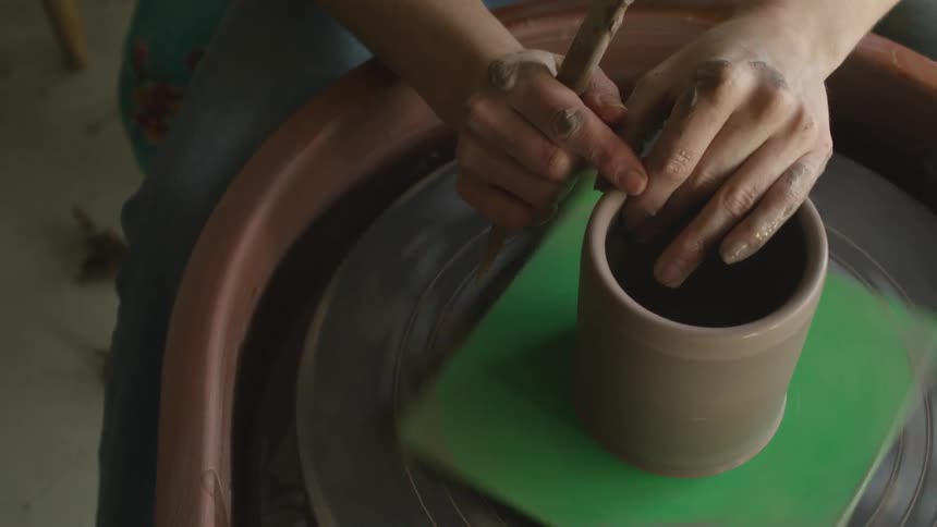 A woman shaping clay on a spinning pottery wheel
