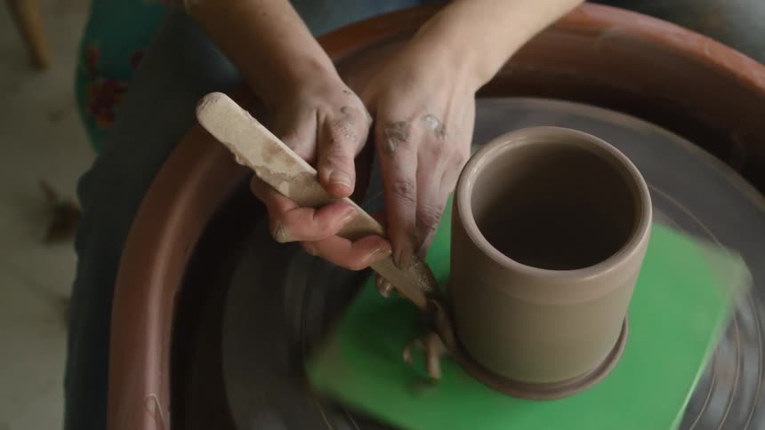 A woman shaping clay on a spinning pottery wheel