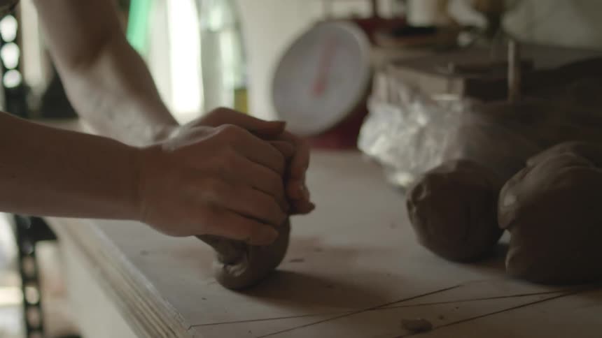 A person kneads clay on a table