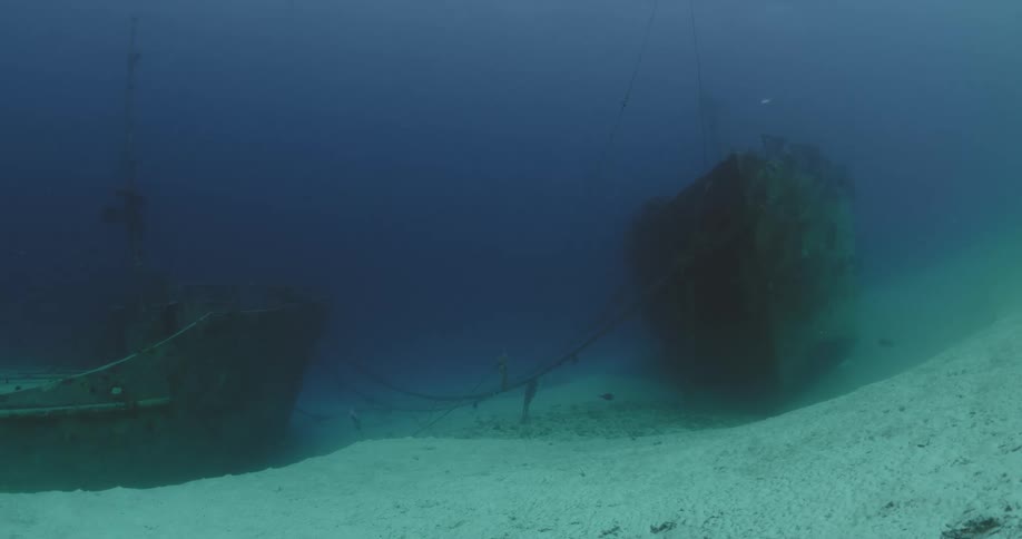 A pair of wrecked ships on the sea floor during the day