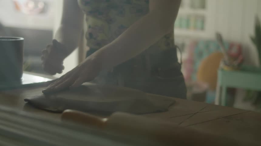 Woman stands at a counter and presses on a freshly rolled pie crust