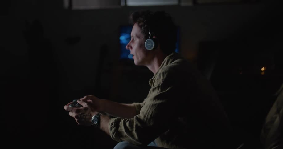 Man wearing a headset sitting on the couch and playing video game