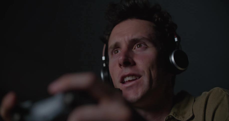 Man wearing a headphone and talking into the microphone while playing video game