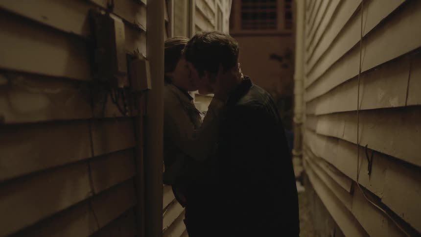 Couple kissing and embracing between two buildings
